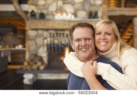 Happy Affectionate Couple at Rustic Fireplace in Log Cabin.