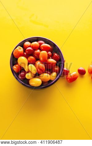 Purple Bowl With Fresh Cherry Tomatoes On Yellow Background