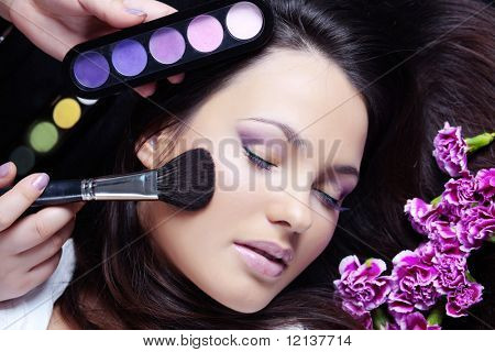 Make-up artist making eye visage to beautiful woman