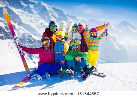 Family ski vacation. Group of skiers in Swiss Alps mountains. Adults and young children teenager and baby skiing in winter. Parents teach kids alpine downhill skiing. Ski gear and wear safe helmets.