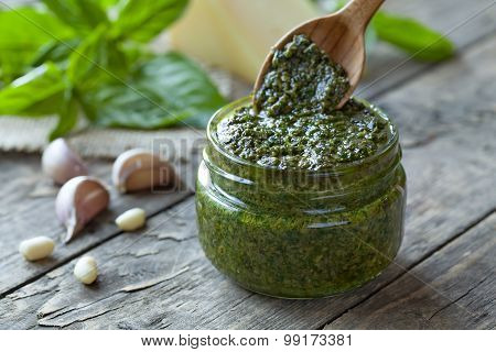 Traditional Italian pesto vegetarian food with basil nuts and olive oil. Wooden spoon gaining portio