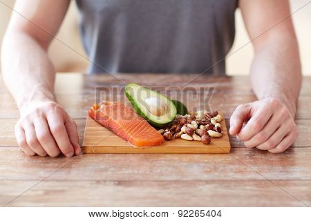 healthy lifestyle, diet and people concept - close up of male hands with food rich in protein on cutting board on table