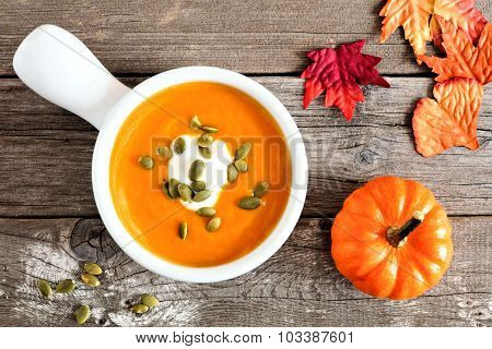 Creamy pumpkin soup on rustic wood background