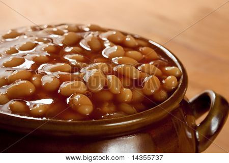 Gebakken bonen in tomatensaus, in een bruine pot.