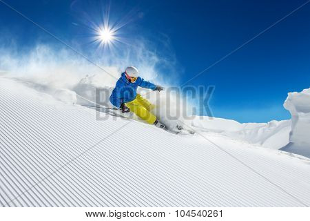 Skier skiing downhill during sunny day in high mountains