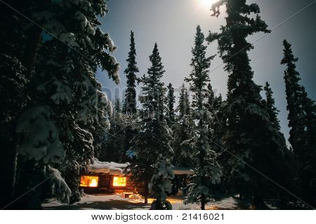 Cozy log cabin at moon-lit winter night