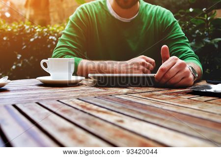 Young man sitting at the table with cup of coffee digital tablet and smart phone