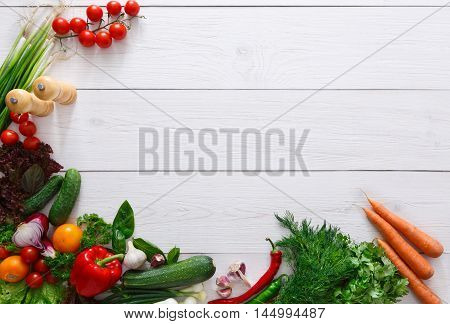 Frame of fresh organic vegetables on white wood background. Healthy natural food on rustic wooden table with copy space. Tomato, lettuce, pepper, zucchini and other cooking ingredients top view