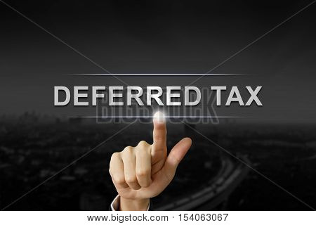 business hand clicking deferred tax button on black blurred background