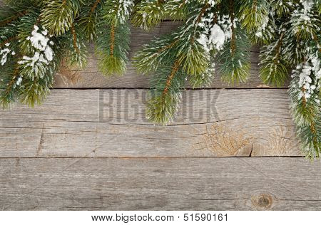 Christmas fir tree covered with snow on wooden board background