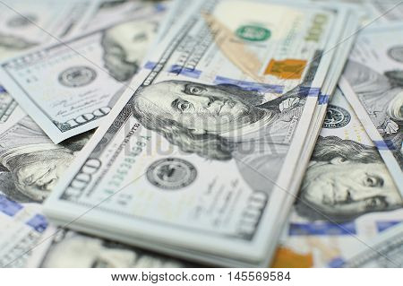 A stack of money. Heap of one hundred dollar bills on money background. Fake money. Shallow depth of field. Selective focus.