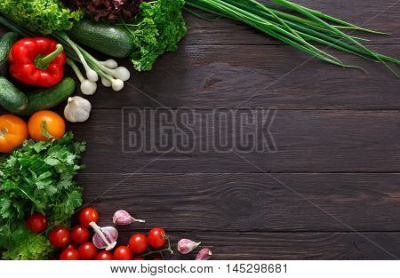 Border of fresh organic vegetables on wood background. Healthy natural food on rustic wooden table with copy space. Garlic, lettuce, carrot, pepper, zucchini and other cooking ingredients top view