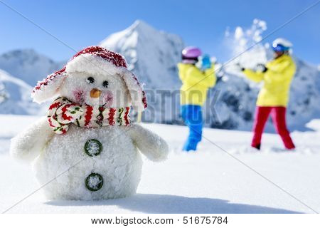 Ski, skier, sun and winter fun - skiers with snowman enjoying winter holidays