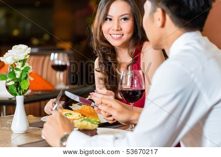 Asian Chinese couple - Man and woman - or lovers flirting and having a date or romantic dinner in a fancy restaurant 