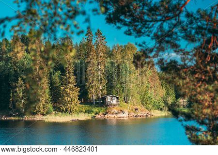 Sweden. Beautiful Swedish Wooden Log Cabin House On Rocky Island Coast In Summer Sunny Evening. Lake