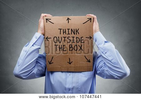 Businessman with cardboard box on his head saying think outside the box concept for brainstorming, creativity, innovation, strategy or individuality