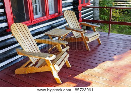 Wooden log cabin cottage porch with adirondack chairs