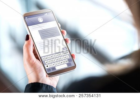 Woman Sending Text Messages With Mobile Phone. Cellphone In Hand With Sms Application On Screen. Per