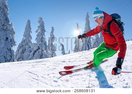 Skier Skiing Downhill In High Mountains Against Blue Sky