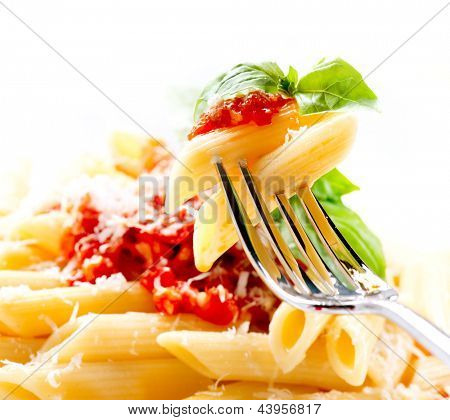 Pasta. Penne Pasta met saus Bolognese, Parmezaanse kaas en basilicum op een vork. Italiaanse keuken. Medit