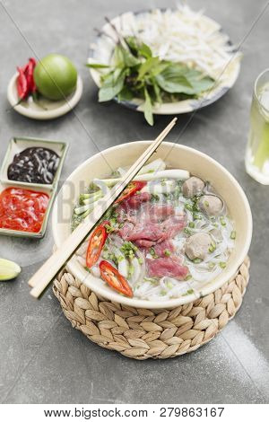 Traditional Vietnamese Soup Pho Bo With Herbs, Meat, Rice Noodles, Broth. Pho Bo In Bowl With Chopst