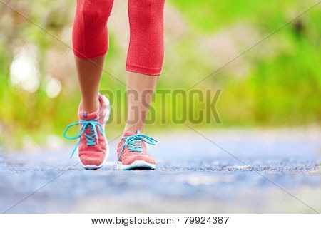 Jogging woman with athletic legs and running shoes. Female walking on trail in forest in healthy lifestyle concept with close up on running shoes. Female athlete jogger training outdoors.