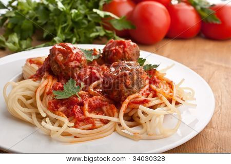 plaat van spaghetti met gehaktballetjes in tomatensaus marinara en ingrediënten op een houten tafel