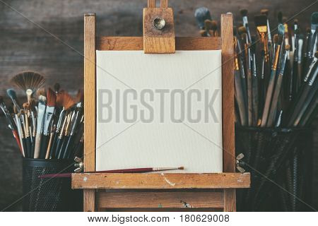 Artistic Equipment In A Artist Studio: Empty Artist Canvas On Wooden Easel And Paint Brushes Retro T