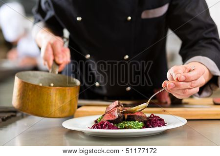 Chef in hotel or restaurant kitchen cooking, only hands, he is working on the sauce for the food as saucier, a Risotto