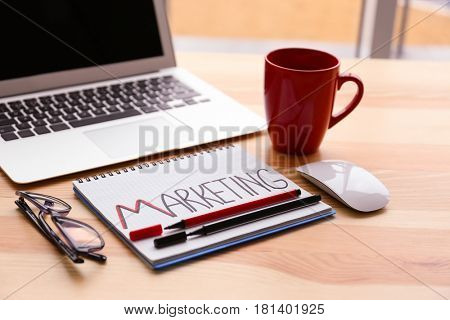 Notebook with text MARKETING on table