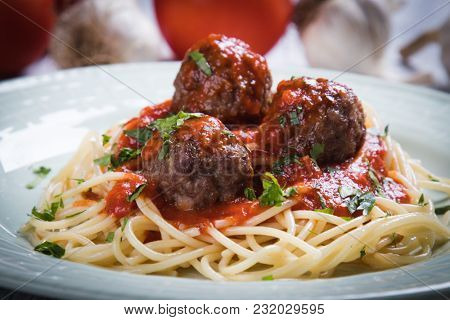 Meatballs served over italian spaghetti pasta with tomato sauce