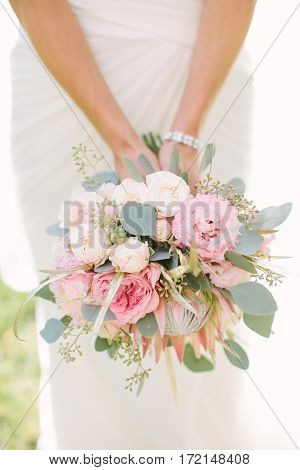 Beautiful woman in a white wedding dress holding a flowers bouquet in hand outside. Wedding bridal bouquet on a white background.