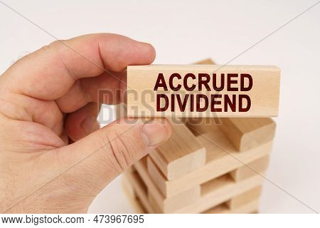 Business Concept. A Man Holds In His Hands A Wooden Block With The Inscription - Accrued Dividend