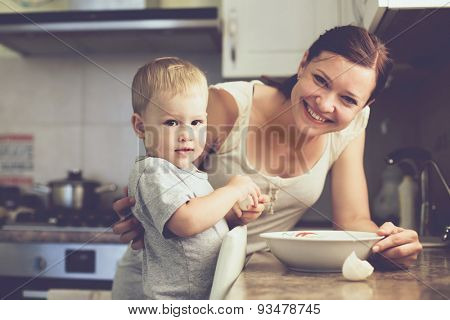 Mom with her 2 years old child cooking holiday pie in the kitchen to Mothers day, casual lifestyle photo series in real life interior