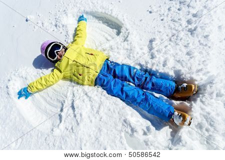 Winter fun - Snow Angel - young skier  girl playing in snow