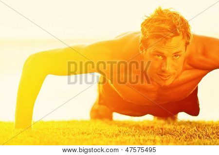 Sport fitness man push-ups. Male athlete exercising push up outside in sunny sunshine. Fit shirtless male fitness model in exercise outdoors. Healthy lifestyle concept.