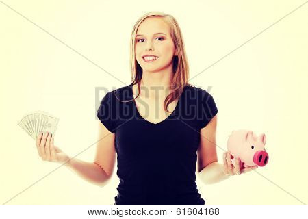 Happy teen holding a piggy bank and dollars