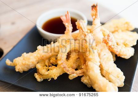 asian kitchen, food, culinary and cooking concept - close up of deep-fried tempura shrimps with soy sauce on table at restaurant