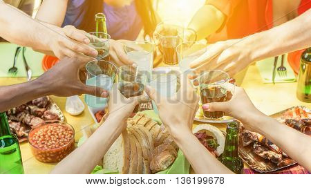 Group of friends toasting with aperitif eating barbecue outdoor - Closeup of hands cheering with cocktails and beers - Friendship summer fun and dinner concept - Soft focus on right bottom hand