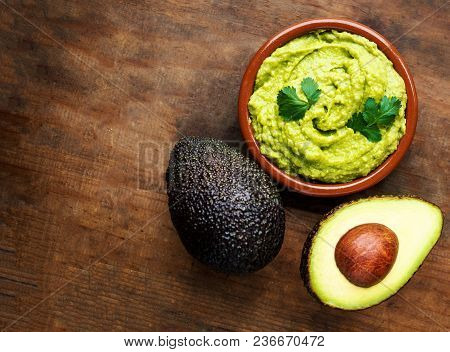 Avocado With Guacamole Sauce On A Dark Wood Background. Half And Whole Avocadoes Close Up. Top View.