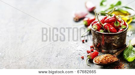 Red Hot Chili Peppers with herbs and spices over wooden background - cooking or spicy food concept