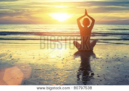 Silhouette of yoga woman meditating on the ocean beach. Fitness. Healthy lifestyle.