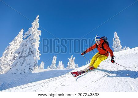 Skier Skiing Downhill In High Mountains Against Blue Sky