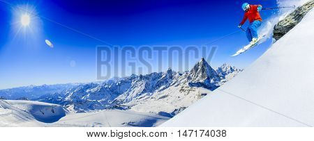 Skier skiing downhill in high jumping from the rocks mountains in fresh powder snow. Snow mountain range with Matterhorn in background. Zermatt Alps region Switzerland