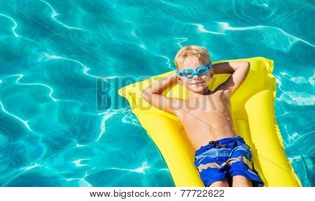 Young Boy Relaxing and Having Fun in Swimming Pool on Yellow Raft. Summer Vacation Fun. Relaxing Lifestyle Concept. 