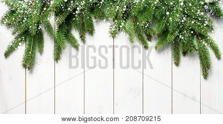 Christmas snow-covered branches on a white wooden background. New Year's background, holiday, christmas, snow, winter, green branches top view with copy space.