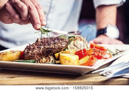 Chef in hotel or restaurant kitchen cooking only hands. Prepared beef steak with vegetable decoration.