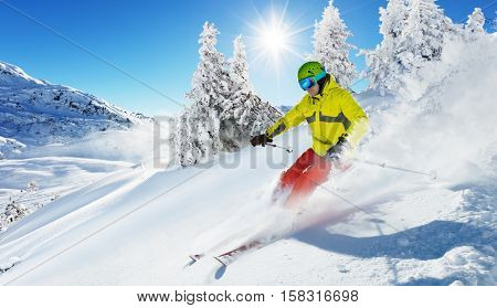 Skier on piste running downhill in beautiful Alpine landscape. Blue sky on background. Free space for text