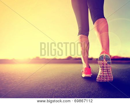  a woman with an athletic pair of legs going for a jog or run during sunrise or sunset - healthy lifestyle concept done with a retro vintage instagram like filter 