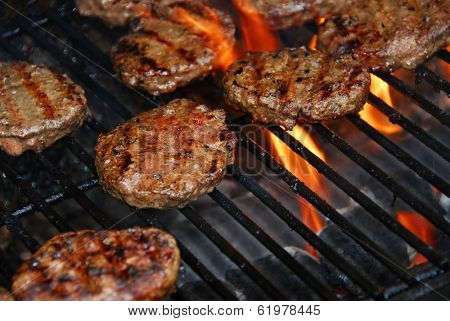 Hamburgers cooking on barbeque grill with flames